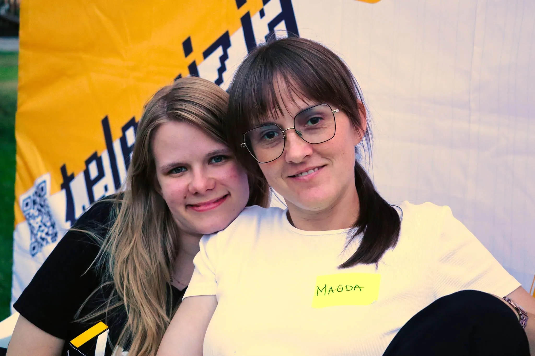 Two smiling women, one wearing a yellow badge.