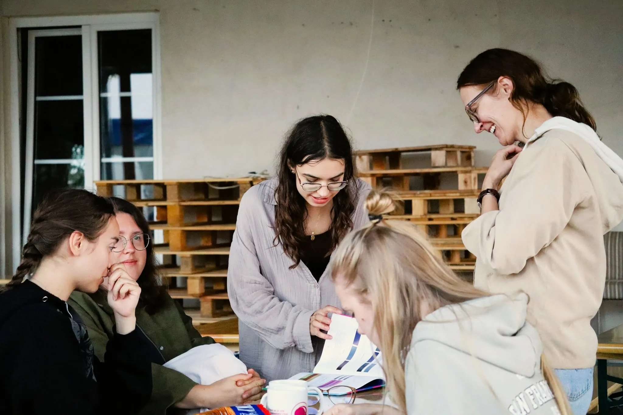 Young women leaning over a book at a table.